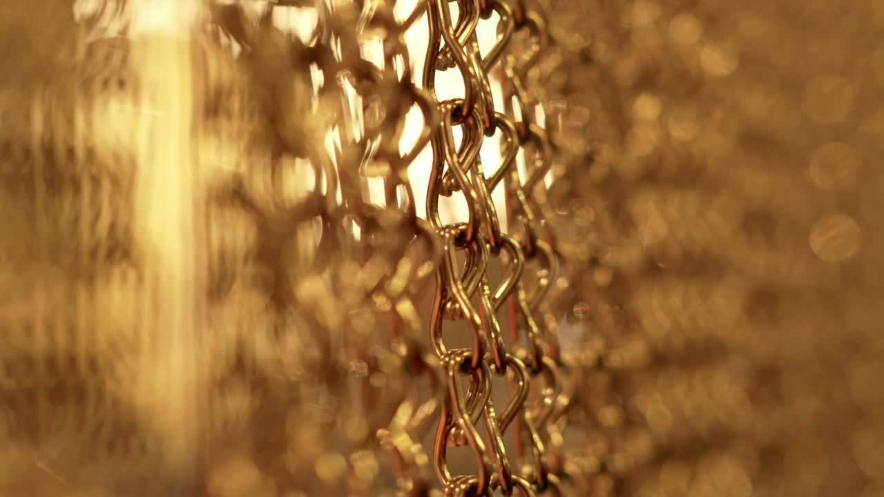 긴 금 사슬의 느리고 부드러운 움직임, 균일한 스, 휴식을 위한 금색 배경, 명상, 휴식, 진정시키기 위한 질감, 반이는 빛, 아래에서 위로 보이는 광경, 흐릿한 빛.