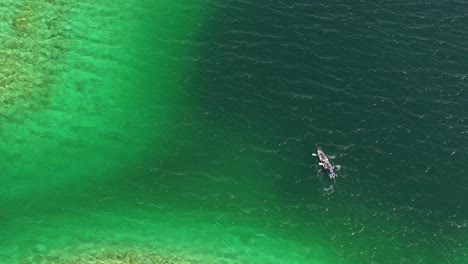 observing from above as a kayaking boat floating the the waters of eibsee in grainau, germany, in a top-down aerial view