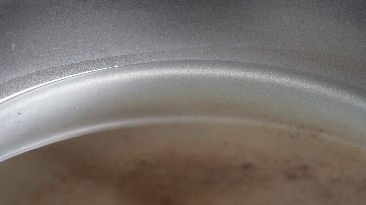 Primo piano di olio vegetale di girasole che si sparge nella padella