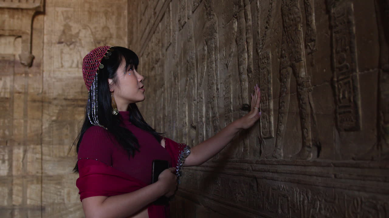 Woman exploring ancient Egyptian hieroglyphs at Dendera Temple, Egypt