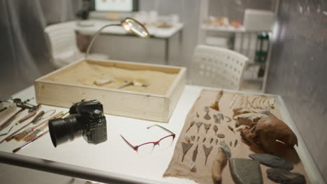 research table with sand-filled box, tools and artifacts in archaeology lab