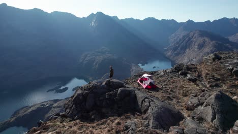 male enjoying the view of the cuillin mountains next to his unfolded tent in scotland