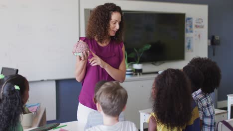 video of caucasian female teacher and diverse school children studying biology in classroom