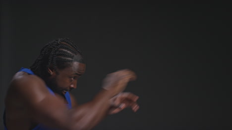 fotografía de perfil de cerca de un boxeador masculino entrenando en el gimnasio preparándose para una pelea contra un fondo de estudio negro