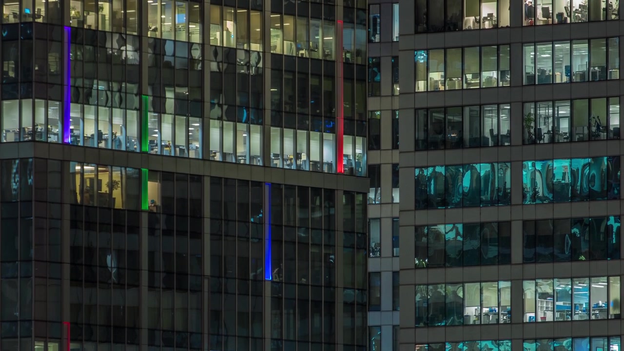 Vista de perto das janelas panorâmicas de escritórios nos arranha-céus do International Business Center da Cidade à noite, timelapse do alto.
