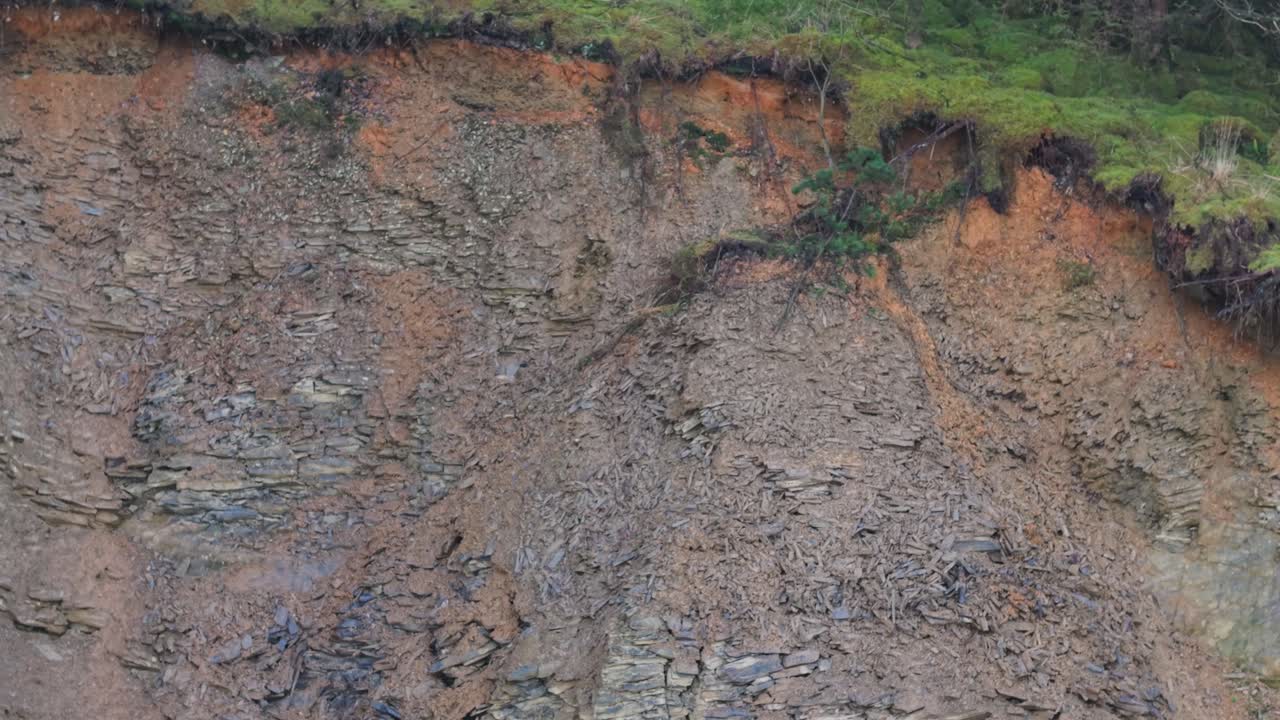 Soil erosion on a rugged hillside in Ireland, exposing layers of rock and earth