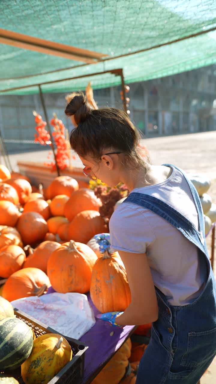 una mujer joven recogiendo calabazas en el mercado de un granjero