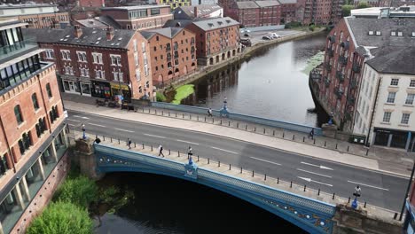 aerial view of a green double-decker bus driving across a victorian bridge above the river aire, surrounded by historic city buildings under daylight