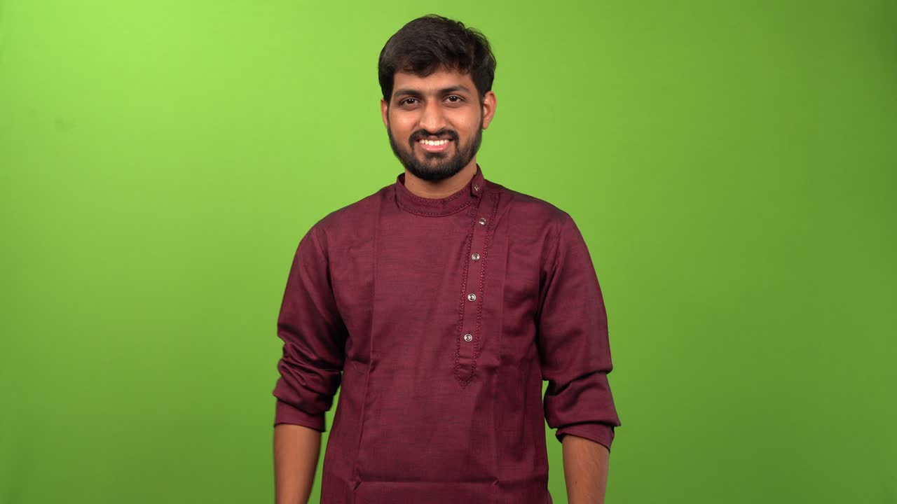 Attractive Indian man showing negative emotion through head and finger movement against a green screen