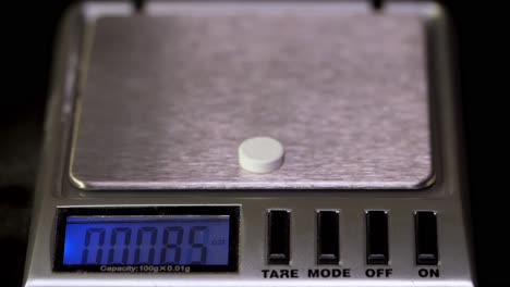 weighing a pill on a digital scale