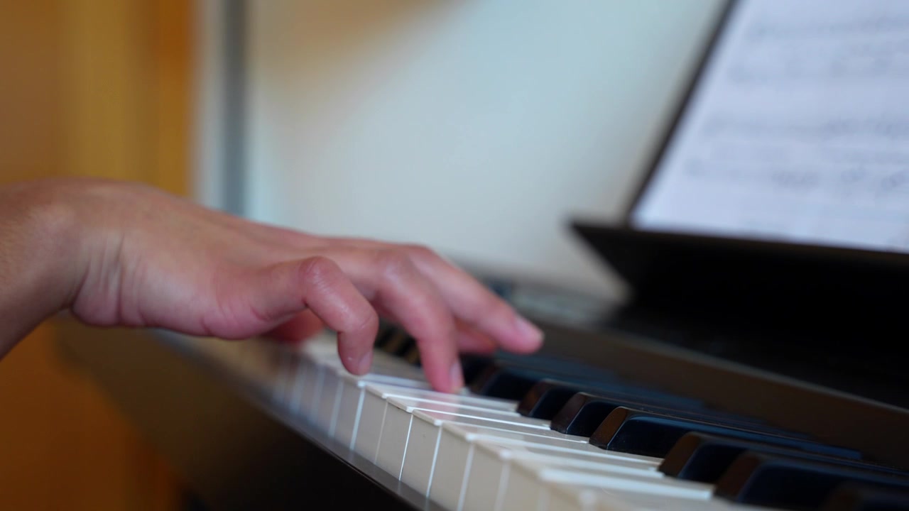 Primo piano delle mani di una donna che suonano una bellissima melodia sulla tastiera del pianoforte mentre legge uno spartito.