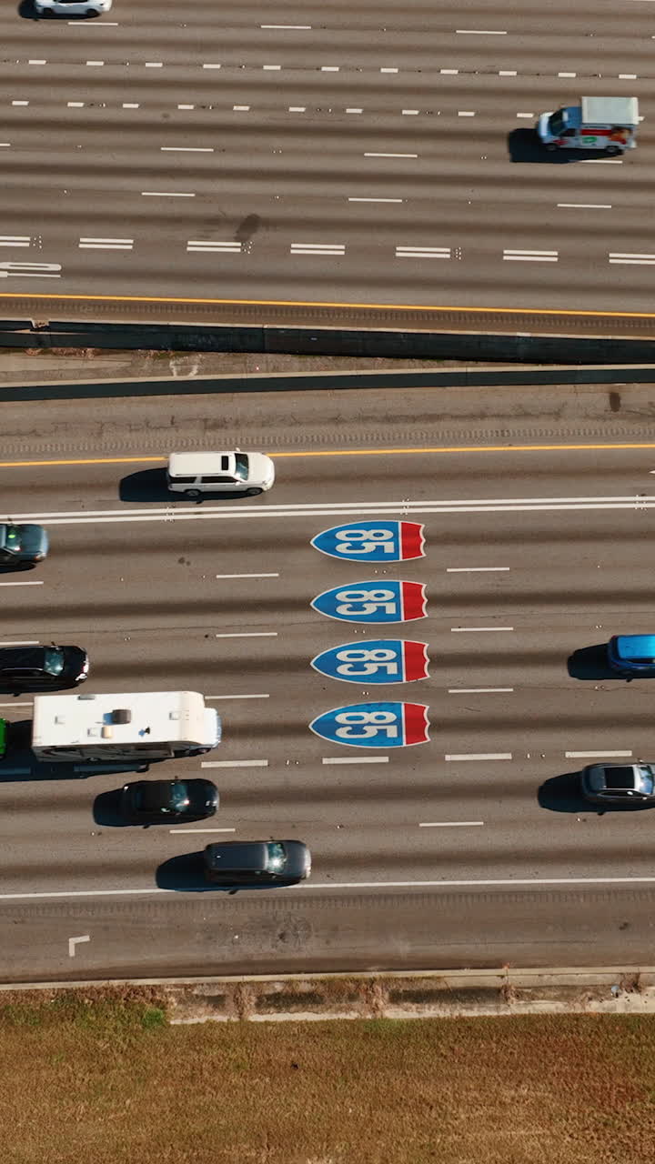 Interstate 85 in Atlanta, Georgia. Aerial top view of cars moving on the road. Wide multi-lane road with heavy traffic, road signs. Vertical video