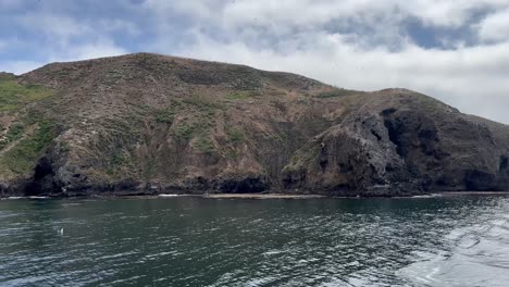 Close-up-handheld-slow-motion-shot-from-a-moving-boat-of-rugged-sea-caves-along-the-coastline-of-Middle-Anacapa-Island,-part-of-Channel-Islands-National-Park-in-the-Pacific-Ocean