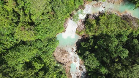 Acercamiento-De-Drones-A-La-Cabeza-De-Una-Cascada-Azul-Cielo-En-El-Bosque-Profundo-Y-Denso