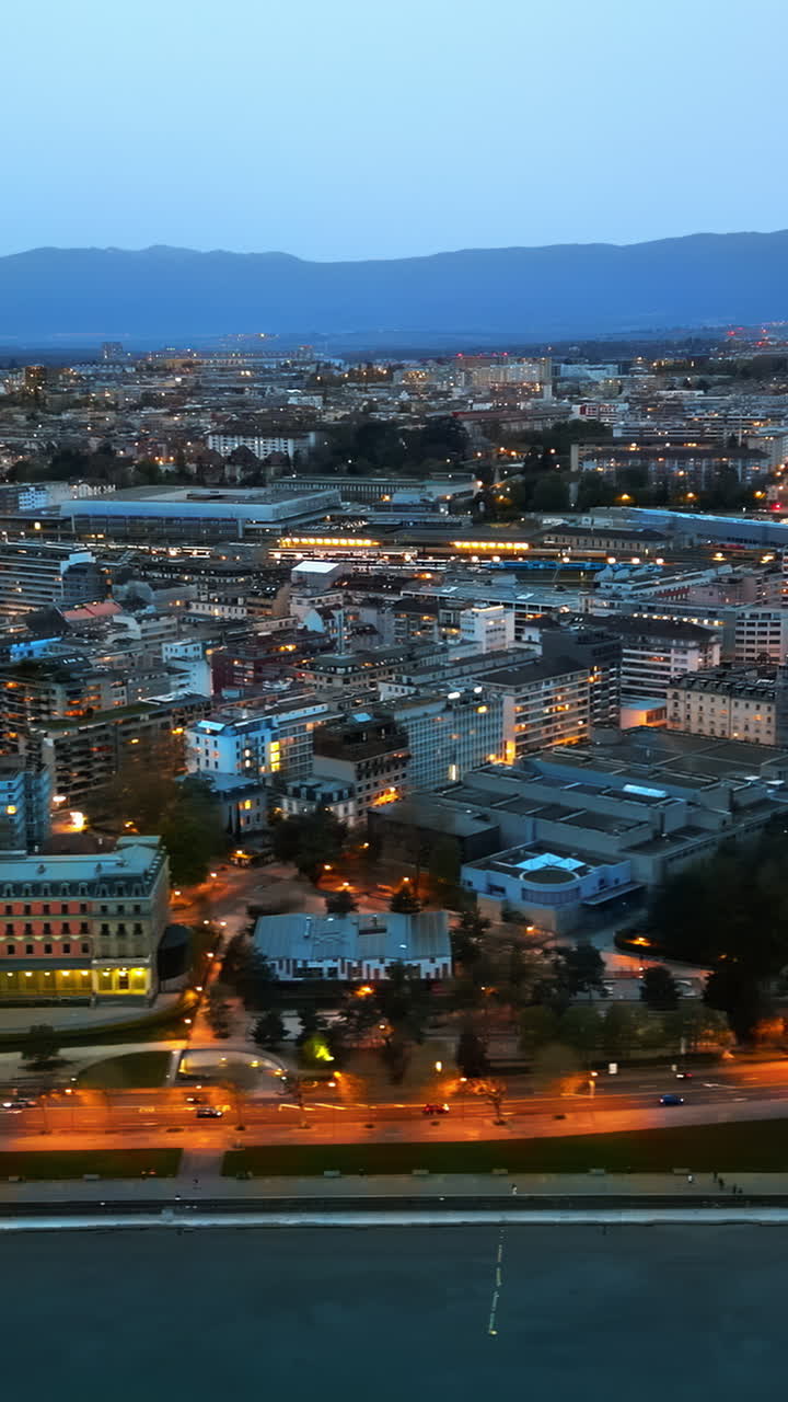Aerial, drone view of the streets and buildings of Geneva, Switzerland in the evening. Vertical