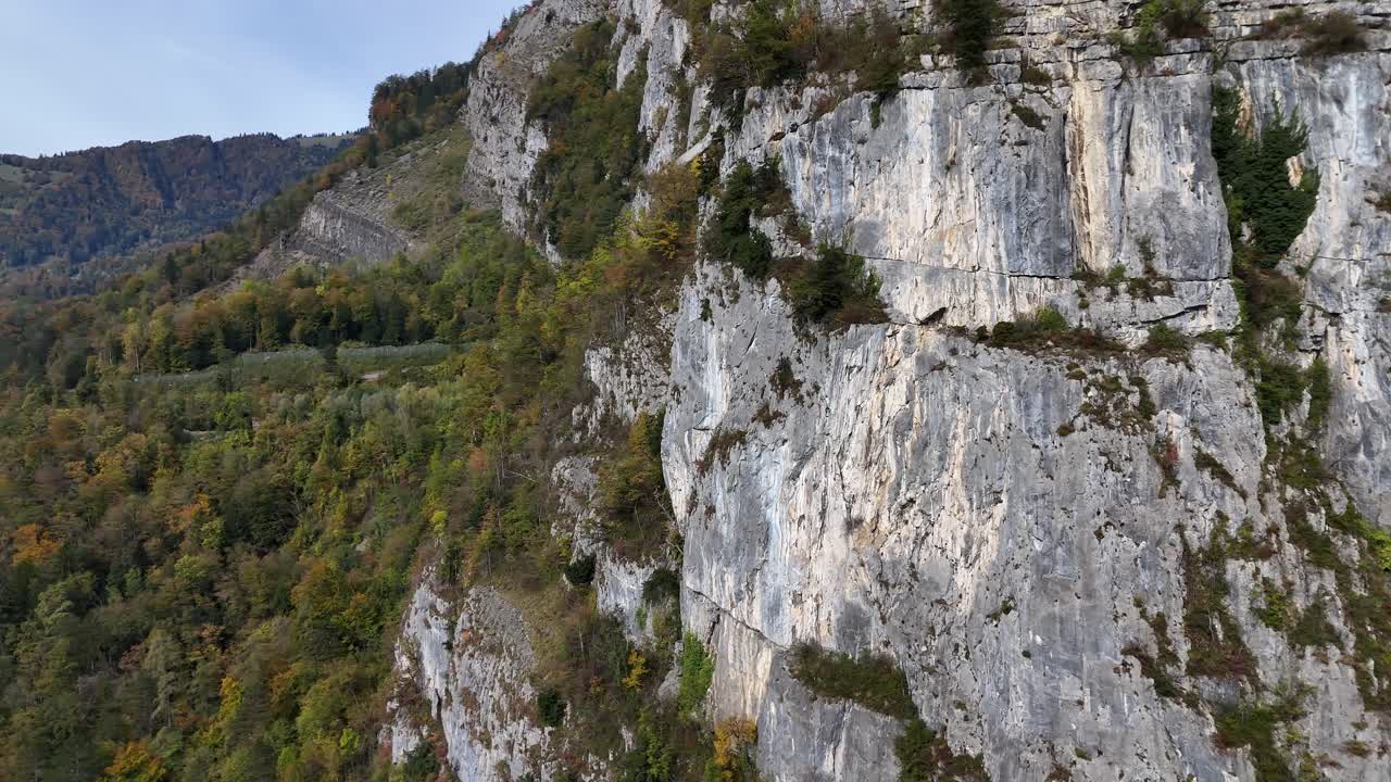 un gran acantilado rocoso en weesen, suiza, con vegetación y un dugout de carretera en las paredes de la cara del acantilado