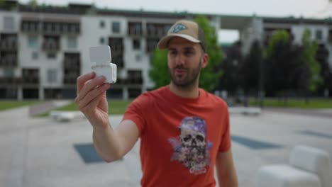 male freelancer using insta360 go 3 action pod in selfie vlog mode outside in urban park