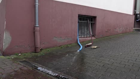 water from the blue hose flows through the drainage canal. wide shot
