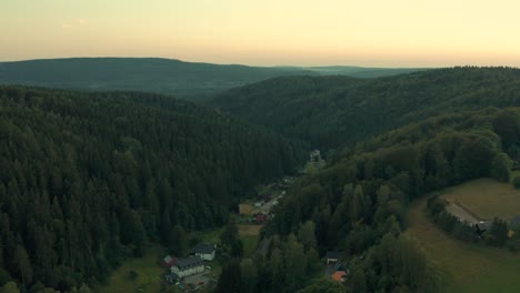 rural houses in valley between high hills covered by evergreen forests