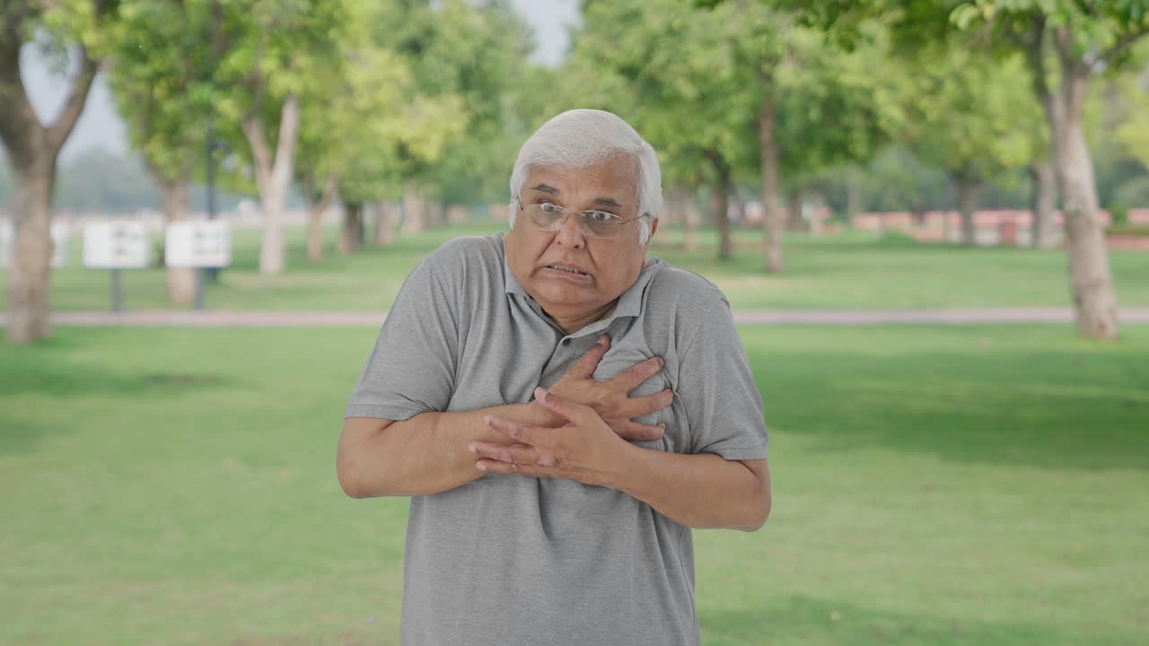 Sick Indian old man having a heart attack in park