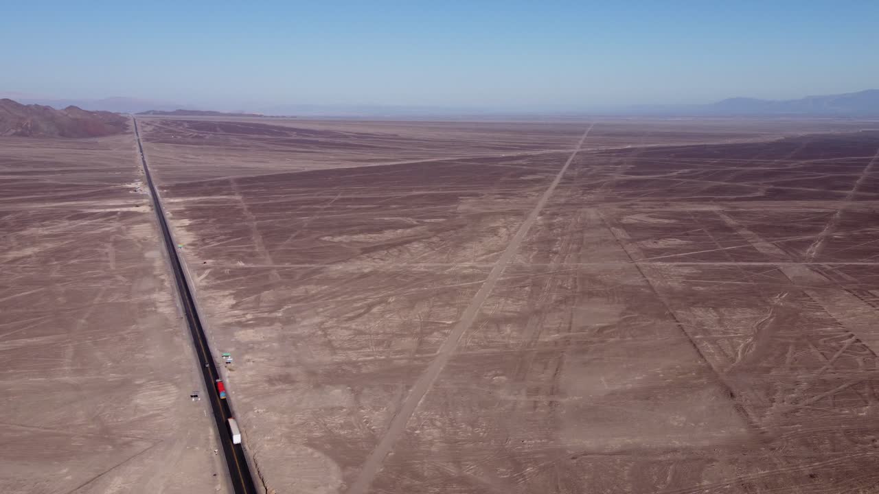 Aerial video of flat desert plateau that holds the famous Nazca Lines. Drone orbits above. Below is a highway and all around are long linear geoglyphs and many more symbols. Located in Nazca, Peru