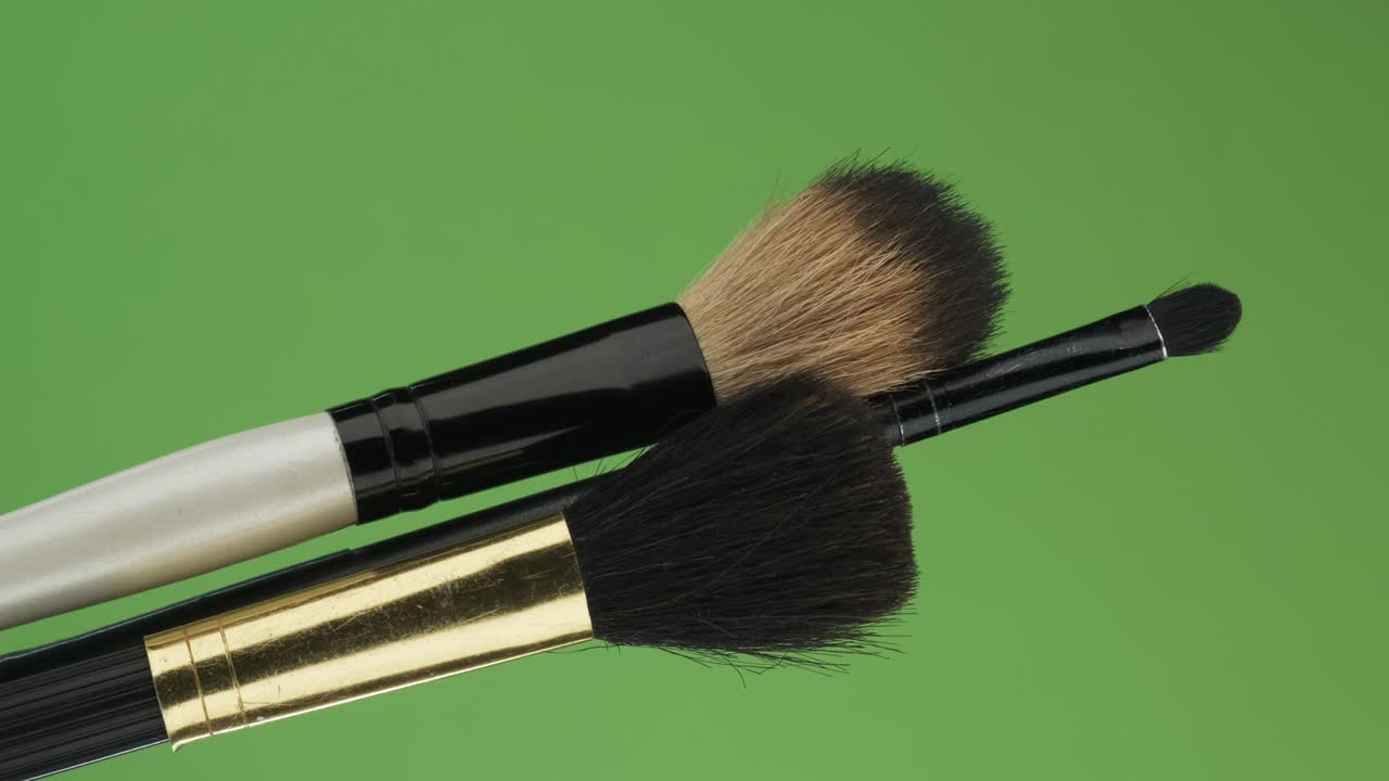 Diagonal rotation of the makeup brushes set. Isolated on green.