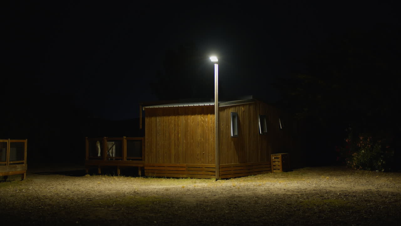 Scena notturna: Una baita in legno illuminata da un singolo lampione