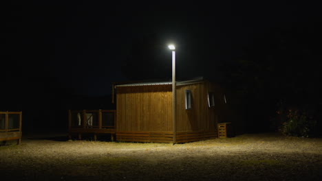 night scene: a wooden cabin lit by a single lamp post