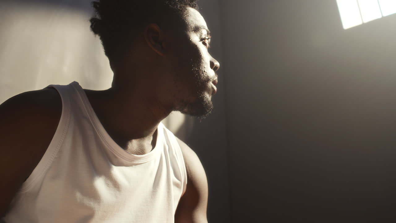 Thoughtful Black Inmate Writing in Notebook in Prison Cell