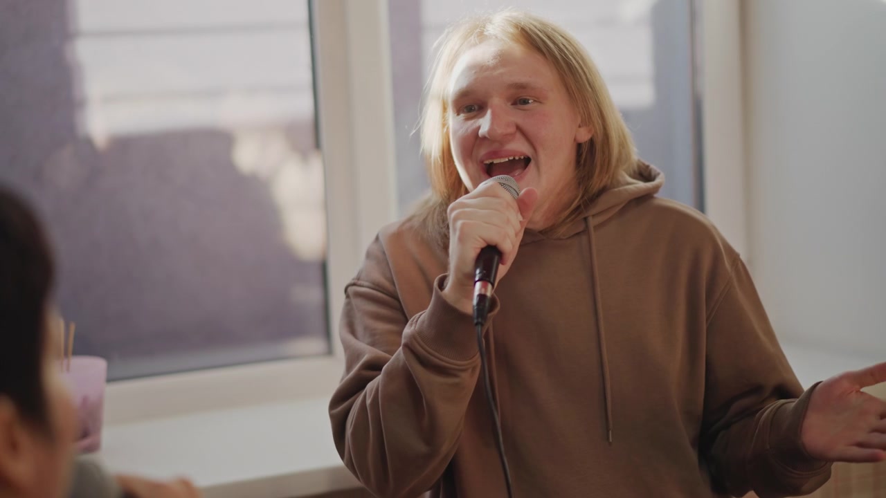 White vocalist celebrating with asian mentor, sunlit classroom stage, handheld microphone closeup, candid laughter and supportive guidance, demo recording vibe, creative breakthrough in music school