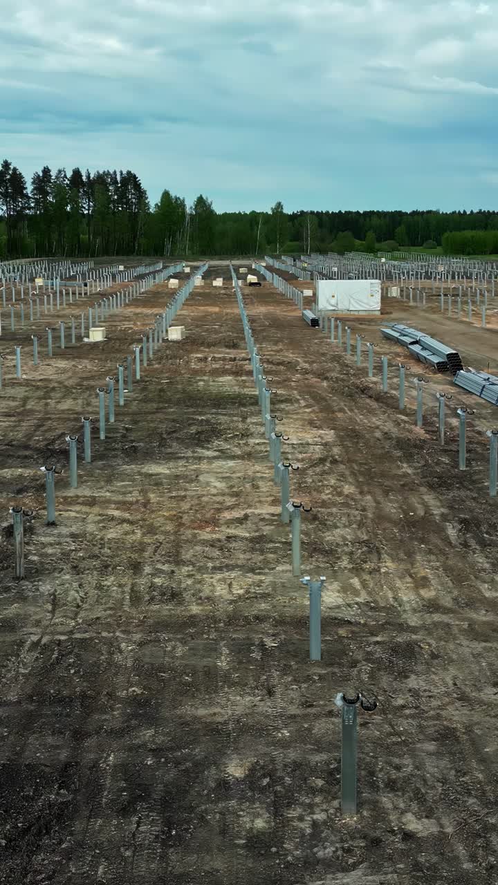 Large construction site where the metal pilings and ground-mounted foundations are being installed for a new utility-scale solar farm and renewable energy power plant - push-in shot