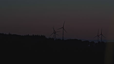 Pan-over-a-group-of-wind-turbines-in-the-highlands,-just-before-sunrise