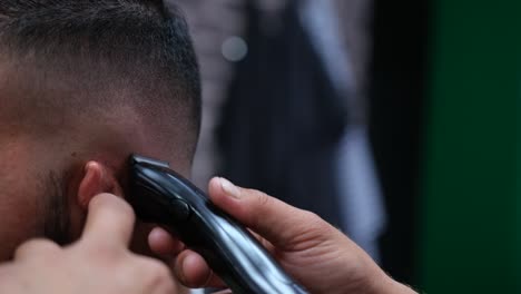 close-up of a barber using an electric razor to give a male customer a very short cut