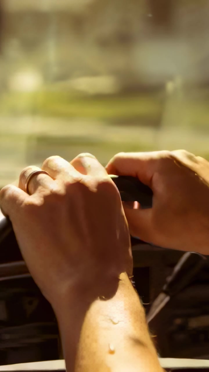 Vertical video: Noticing water droplet, driver lifting right hand adjusting wedding band at wheel