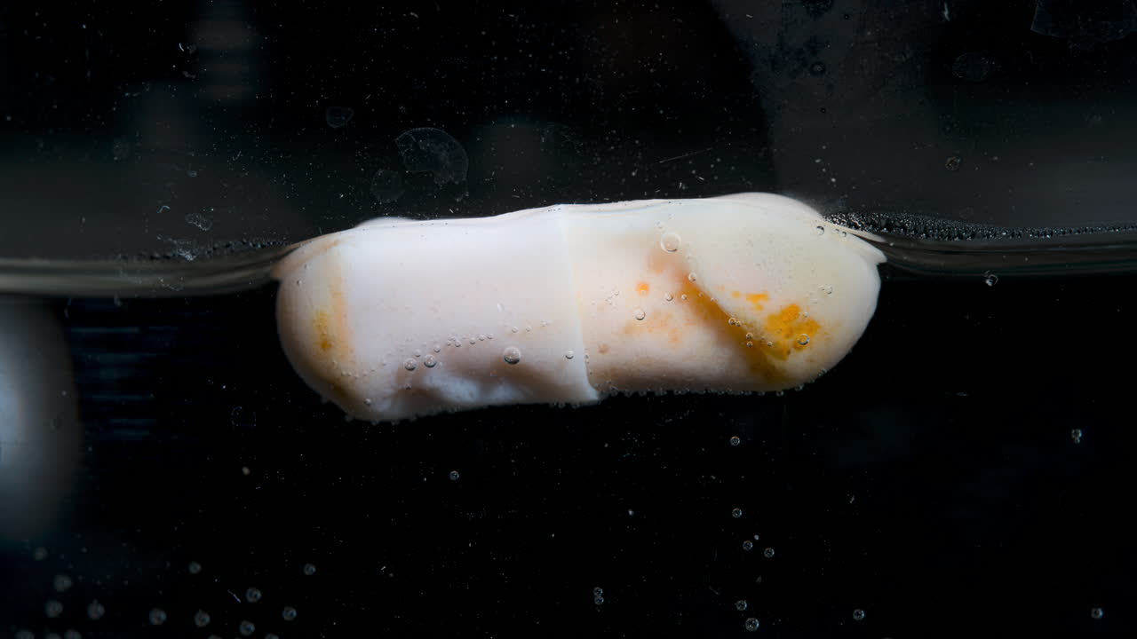 Pill dissolving in liquid, showing bubbles forming around it as it breaks down