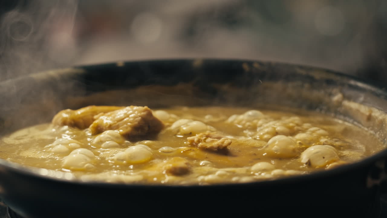 Green boiling sauce with chicken texture close-up macro. Cooking green chicken curry with spices by wooden spoon at home.