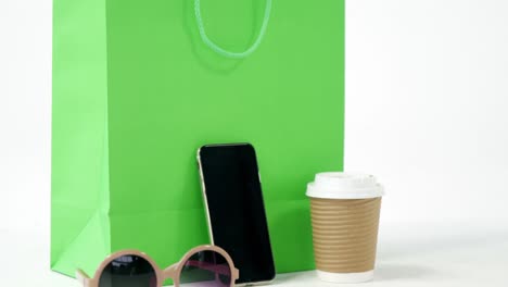 bolsa de compras, teléfono móvil, gafas de sol y café