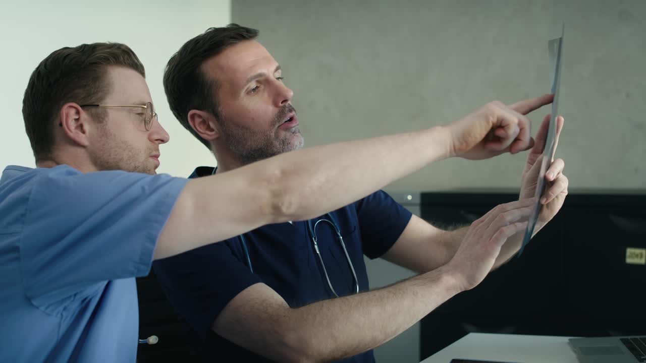 두 남성 백인 의사 가 의학적 인  ⁇ 스레이 스캔 을 논의 하고 있다