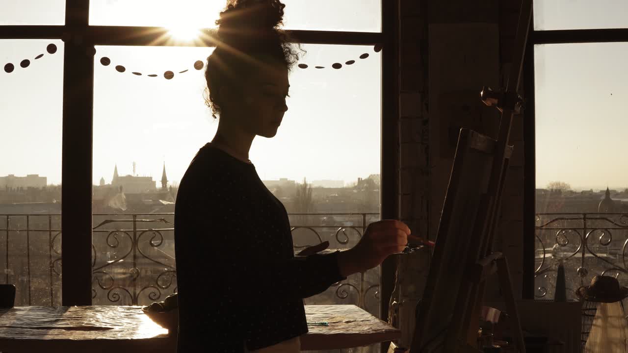 Cute female artist in her 20's is drawing picture on easel.