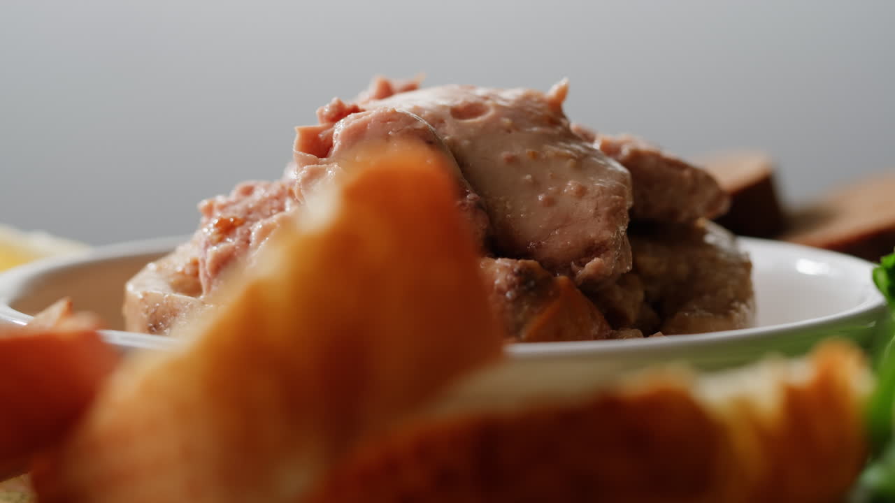 Smoked cod liver in oil in open tin can with fresh greens on wooden table. Seafoods delicacy. High quality 4k footage