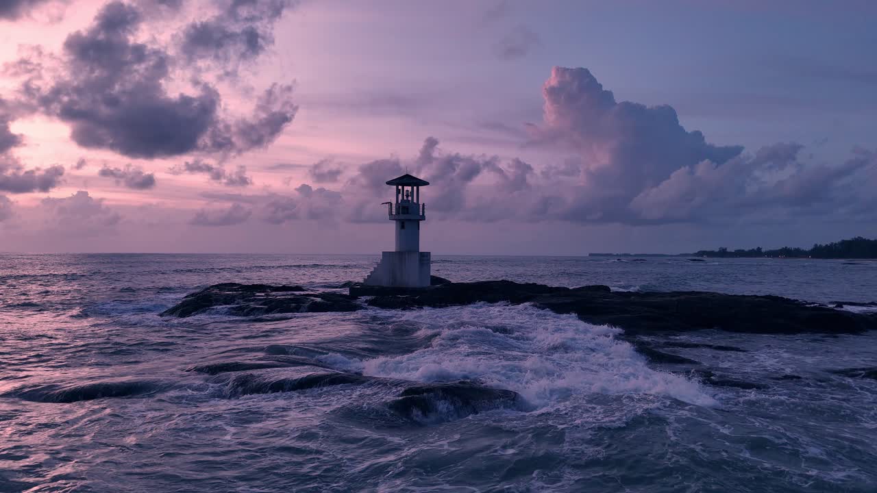 Lighthouse on rocky coast at sunset