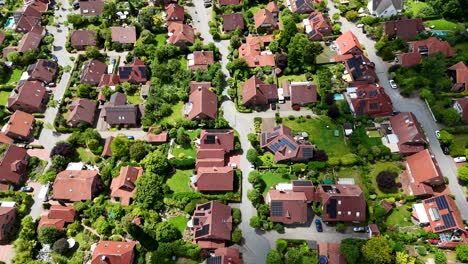 solar panels on single family houses in calm neighborhood of america. aerial top down shot. orange tile roofs on homes. street and road with green trees and sunlight