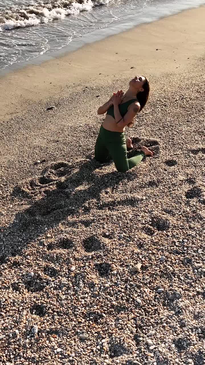 Woman performing heart opening yoga pose on sandy beach