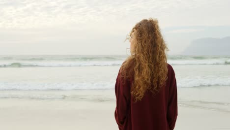 Vista-Trasera-De-Una-Joven-Caucásica-Parada-En-La-Playa-Y-Mirando-Al-Mar-4k