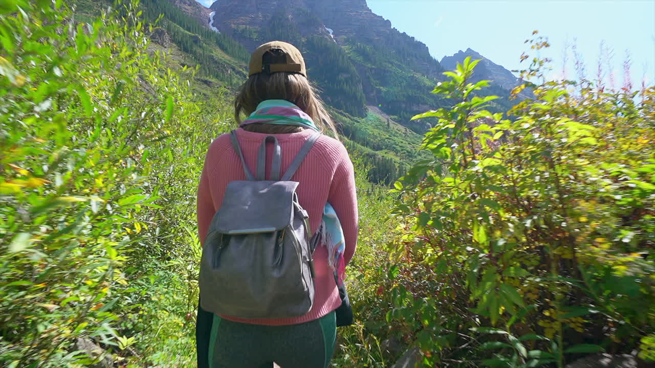 Cinematic gimbal stabilized walking through hiking trail Maroon Bells Wilderness Aspen Snowmass Rocky Mountain Colorado late summer tall green grass stunning morning magical follow women model actress