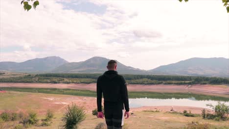 man steps at the end of a landscape enjoying the view of the lake and green nature