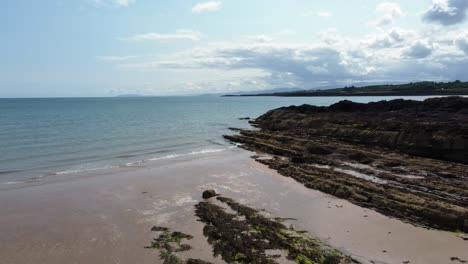 Aerial-view-Traeth-Lligwy-Jurassic-rocky-weathered-rugged-Anglesey-shoreline,-pull-back-shot