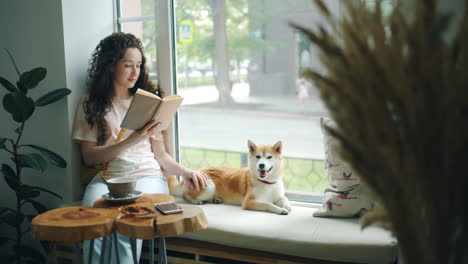 woman reading a book in a cafe with her dog