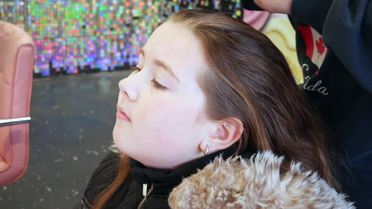 una joven en el salón de peluquería mientras su cabello está siendo peinado suavemente