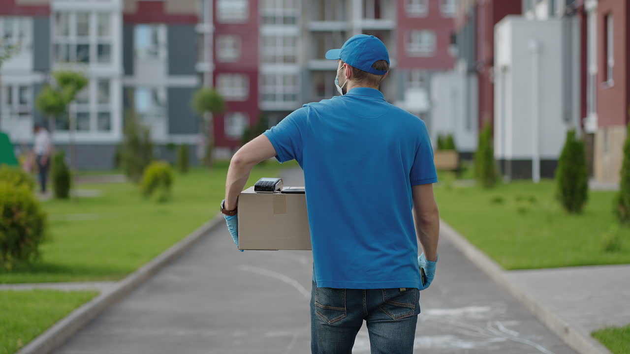 A delivery man carries a package to customers in a residential area. Grocery delivery and online shopping